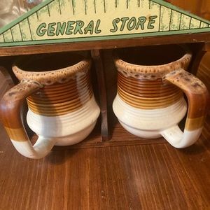 A cup holder that looks like a store that hangs on the wall or sits 2 cups